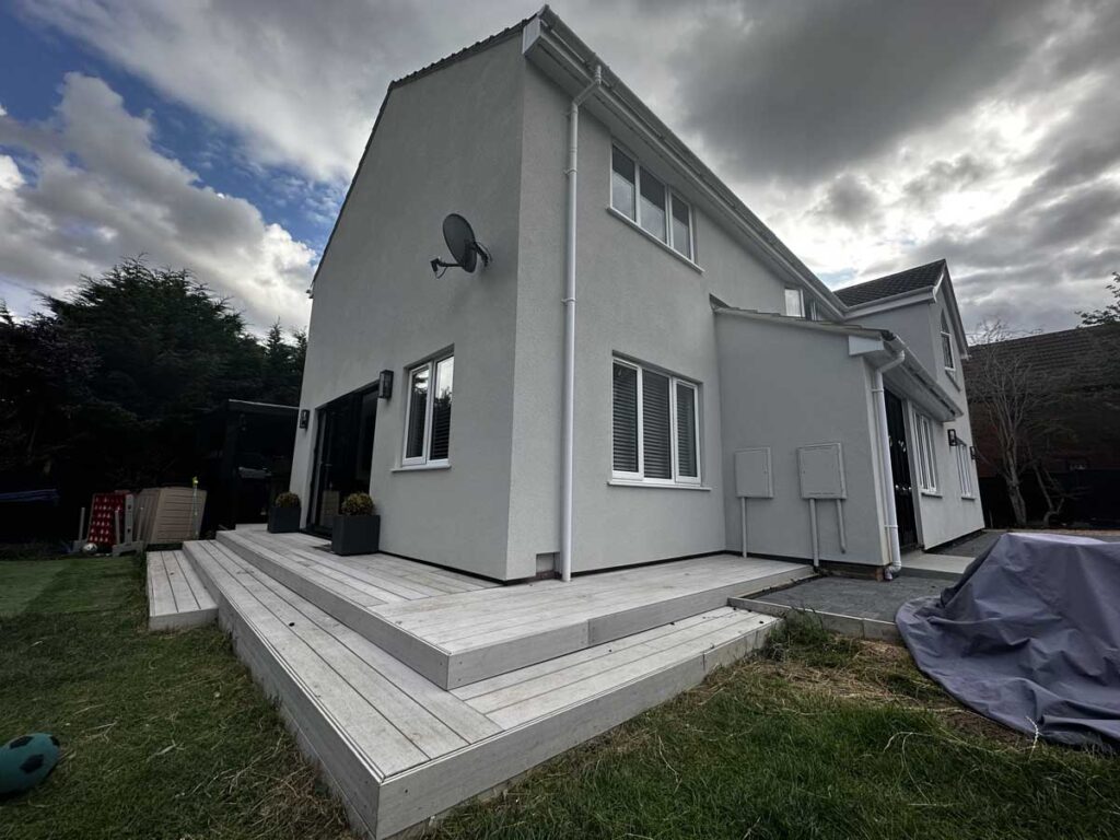 Newly built house extension with clean white render finish and patio area